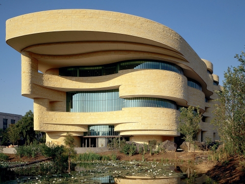 Exterior of building with undulating facade and earth-toned stones.