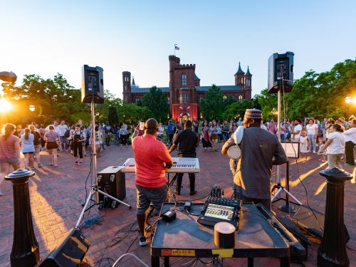 An outdoor concert in front of a large red brick building.
